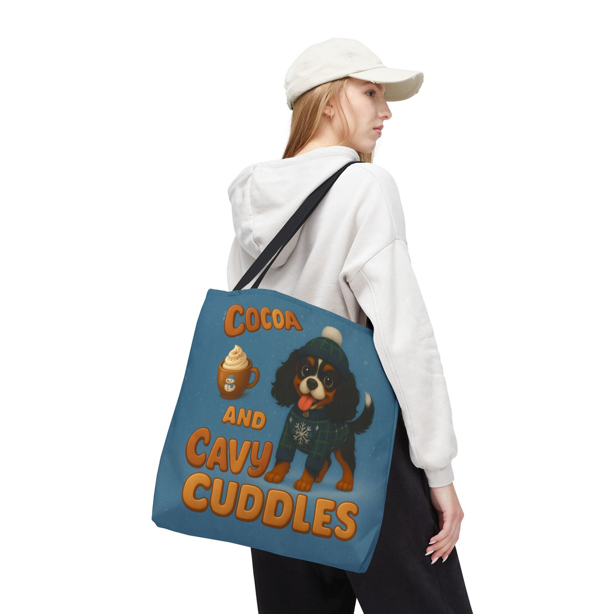 Woman in a cap carrying the Tricolor Cavalier Cocoa and Cavy Cuddles tote over her shoulder, back view