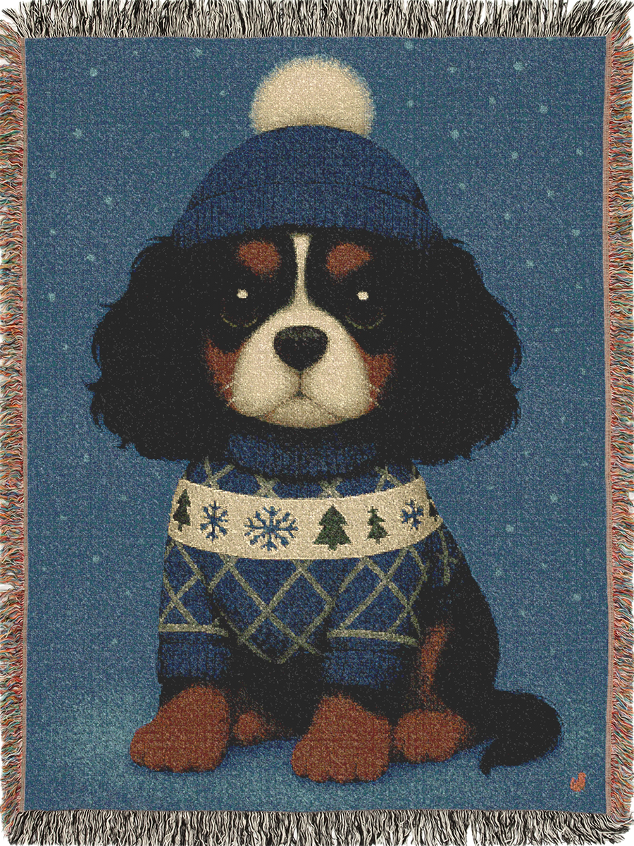 Cavy Comfort woven throw blanket, front view with fringed edges, Tricolor Cavalier King Charles Spaniel puppy in a knit beanie and sweater in the snow