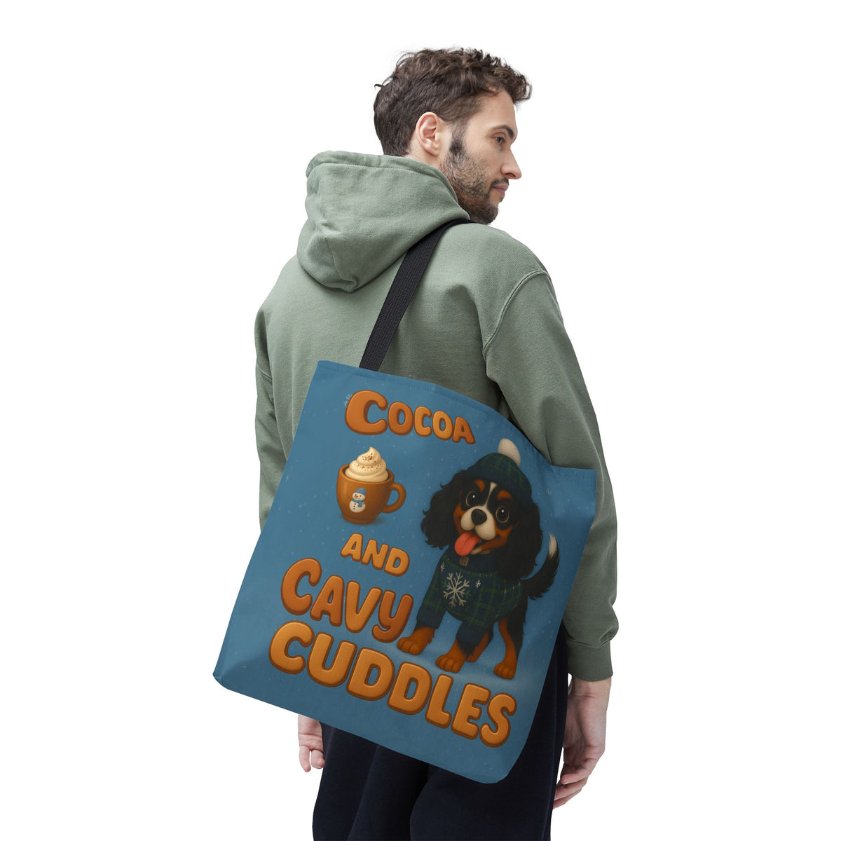 Man in a green hoodie carrying the Tricolor Cavalier Cocoa and Cavy Cuddles tote over his shoulder, back view